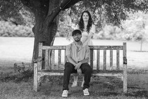 A couple shares romantic moments on park benches in black and white photography.