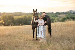 Romantic photoshoot in a golden field at sunset with a horse and couple.