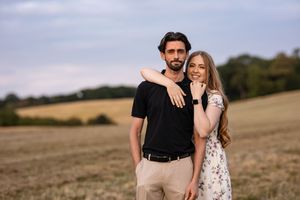 Romantic couple photoshoot in a rustic field during sunset.