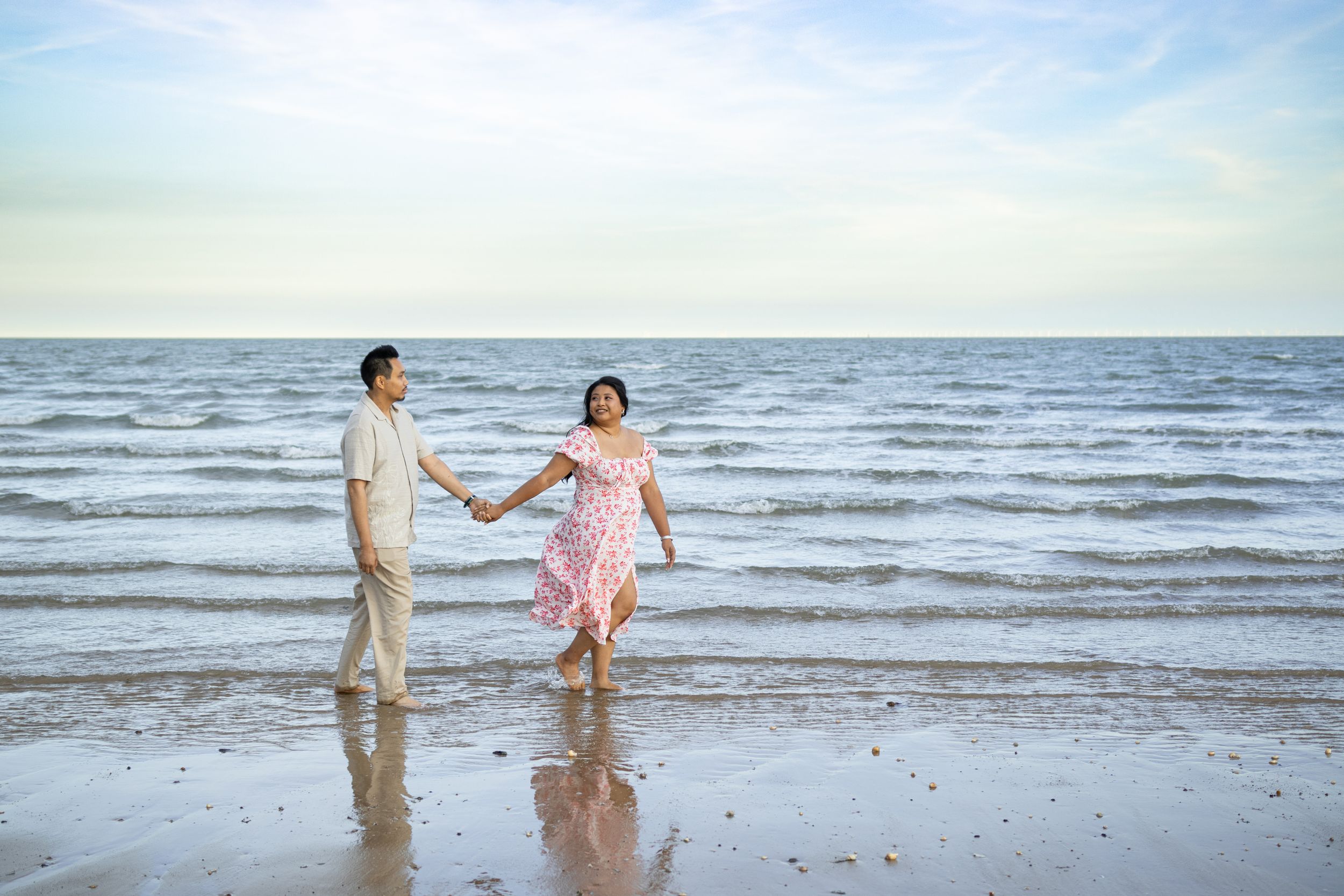 A couple splashing and playing in the ocean waves at sunset.