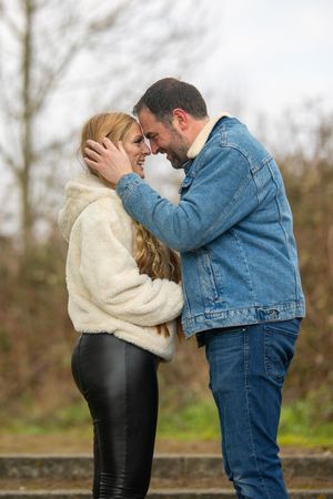 A couple in winter wear shares an intimate moment outdoors.