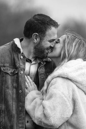 A close-up black and white portrait of a couple sharing an intimate moment.