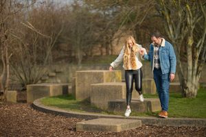 A couple walks through a park pathway during autumn.