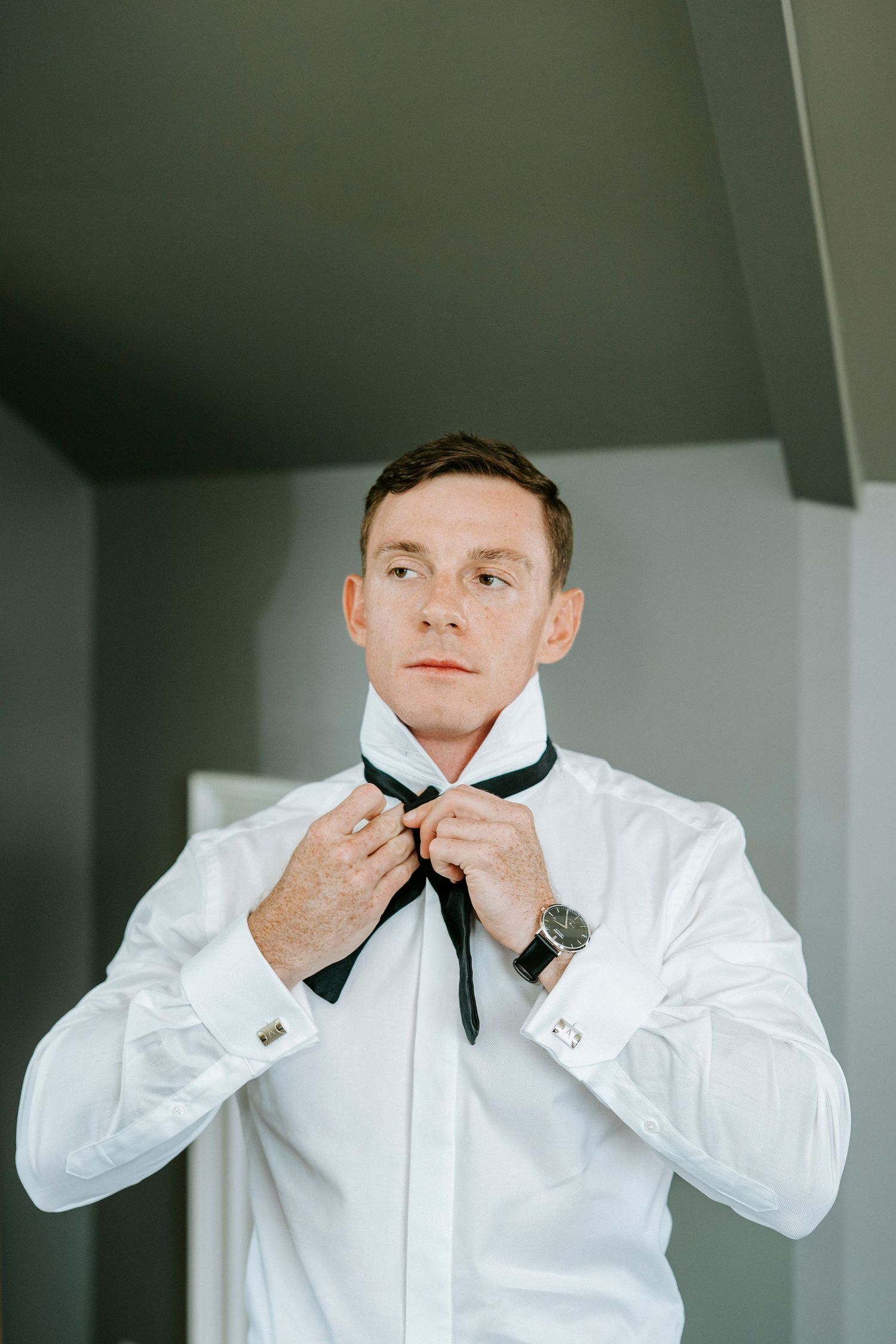 Close-up sequence showing someone adjusting a black bowtie while wearing a crisp white dress shirt.