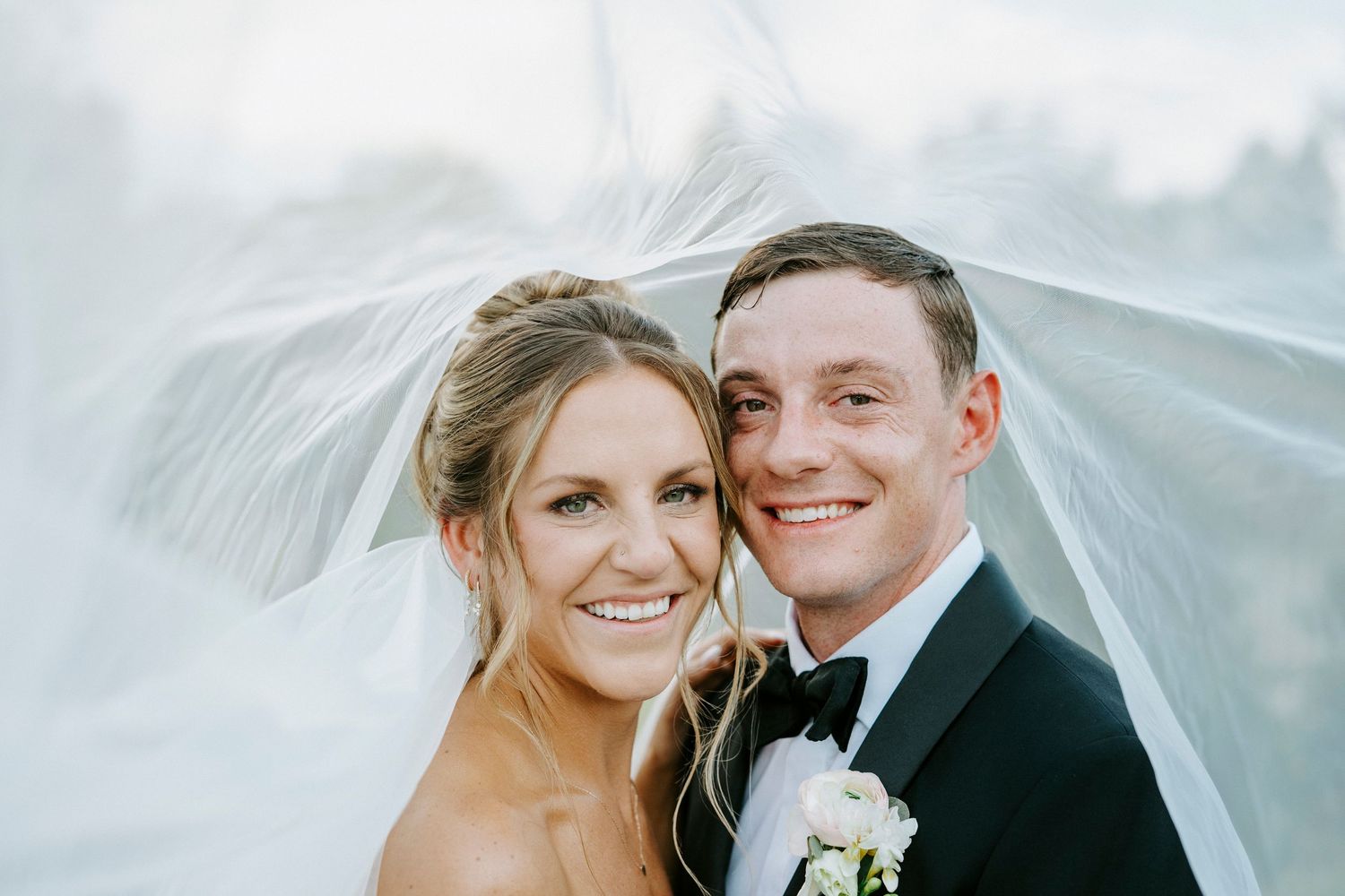 A romantic series of wedding photos showing a bride and groom smiling together in flowing veils against a bright sky background.