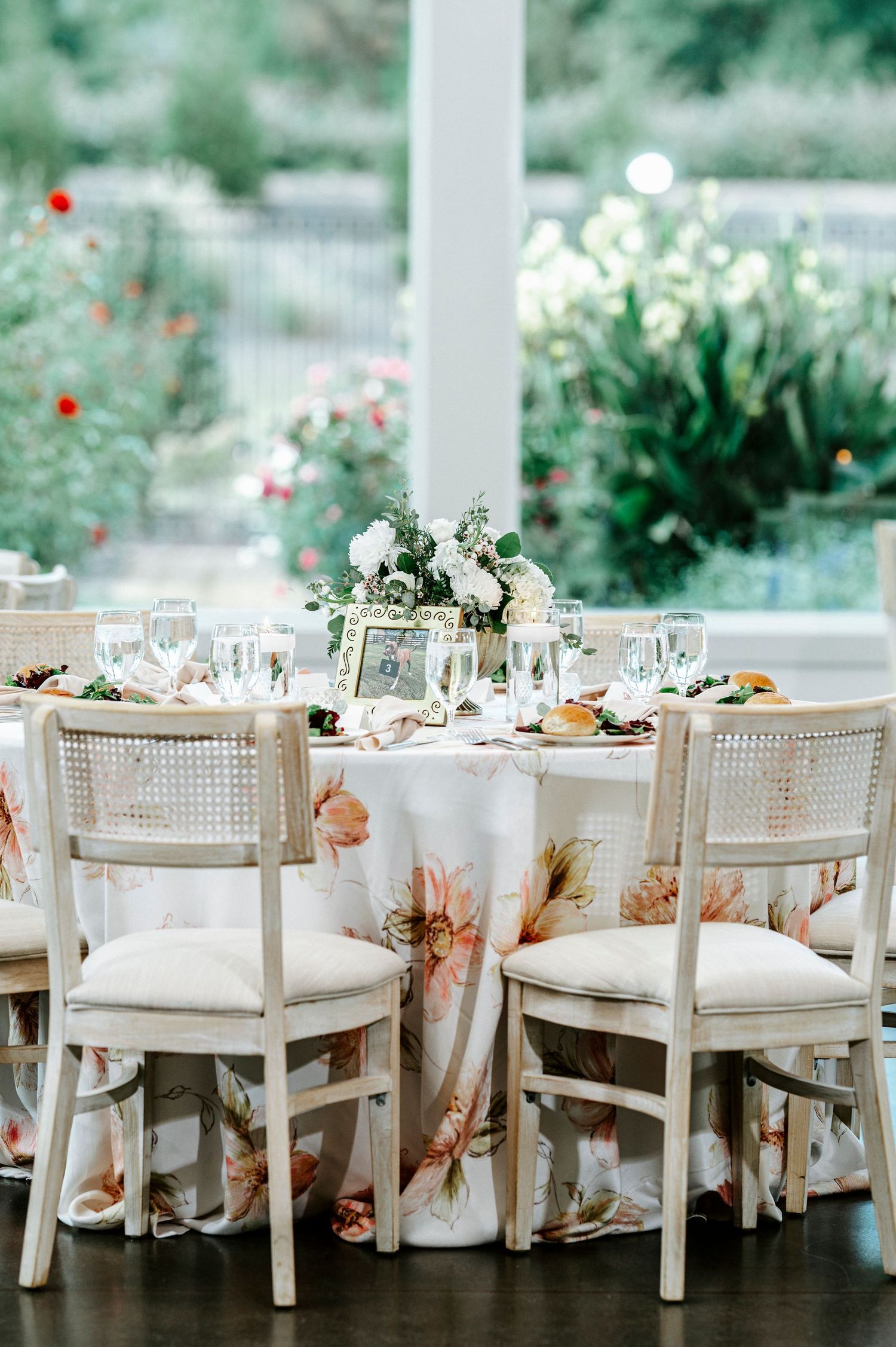 Elegant white dining chairs with cane backs arranged at wedding reception tables with floral centerpieces.