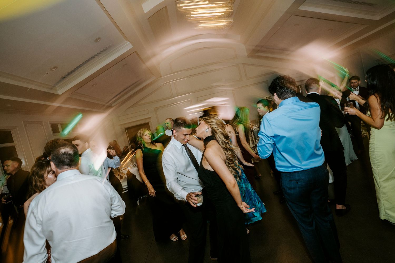 Blurred motion shots of wedding reception guests dancing in a dimly lit ballroom.