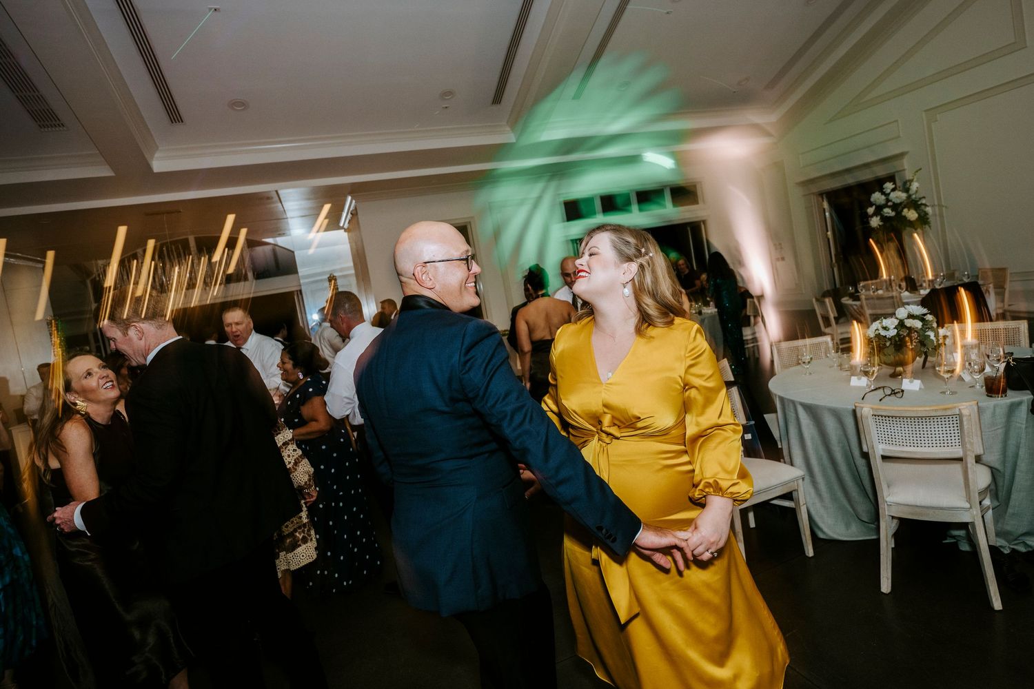 Wedding reception guests dancing joyfully under party lights in a ballroom setting.