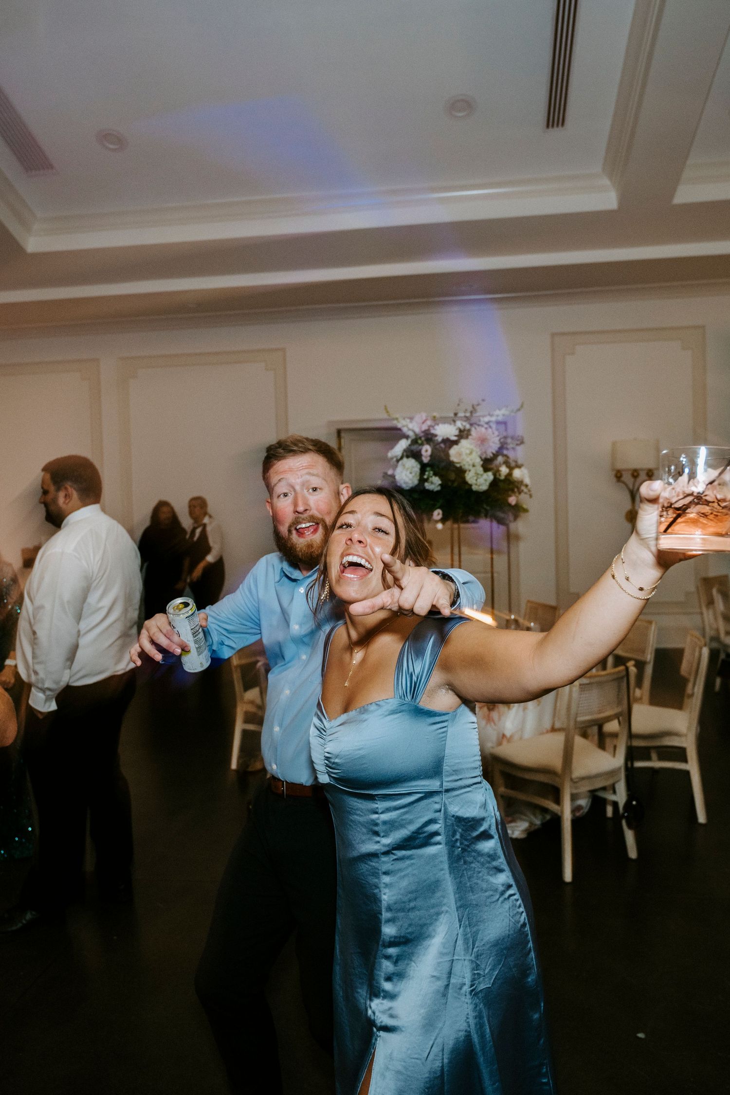 Wedding reception dance sequence showing party guests and blue dresses in a dimly lit ballroom.