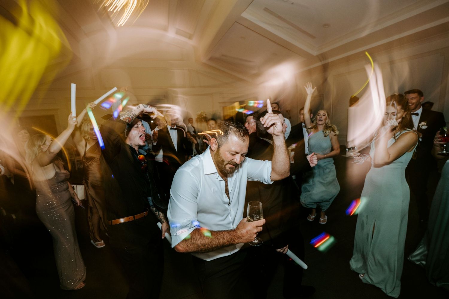Dynamic nighttime wedding reception dance party with colorful yellow lighting.