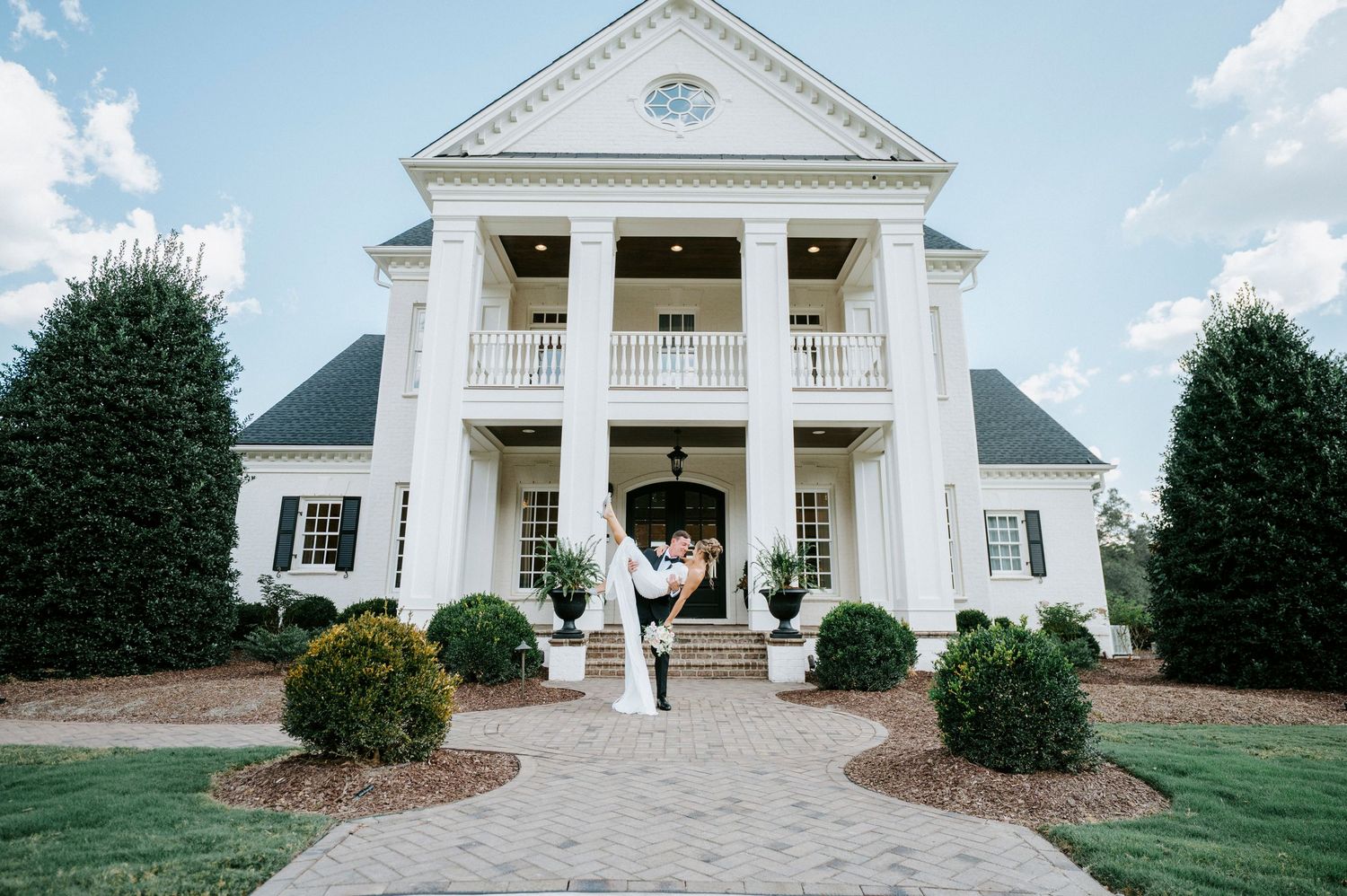 A stately southern mansion wedding venue with classic white columns and symmetrical architecture.