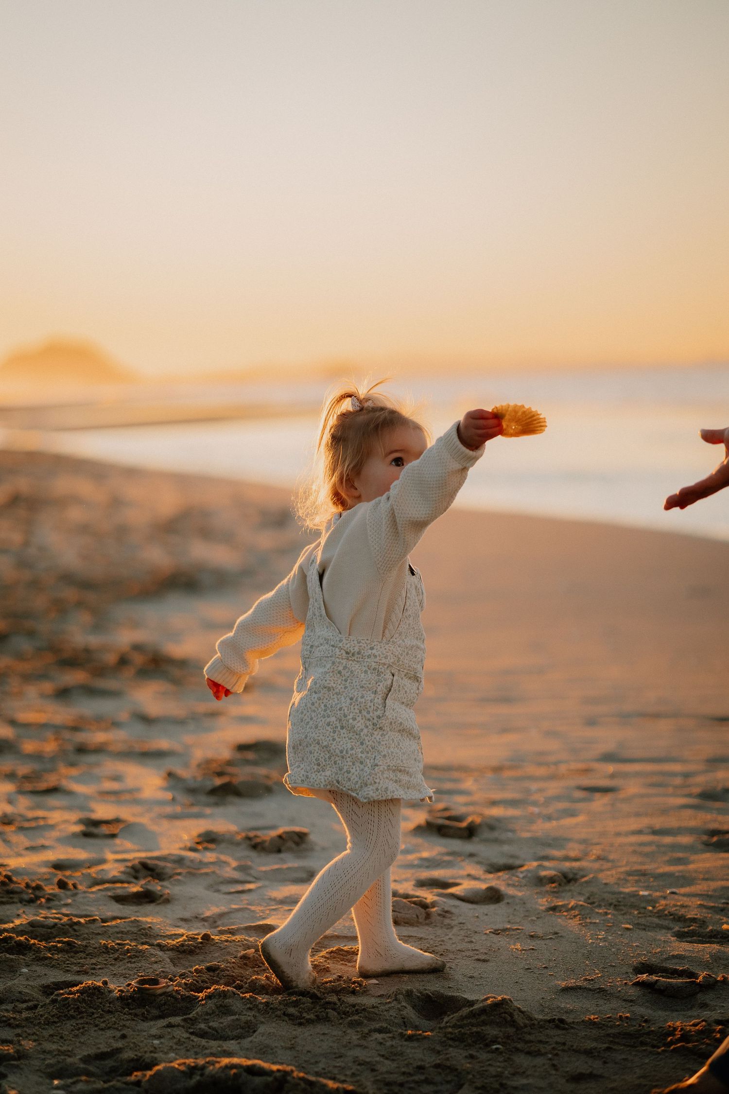Family enjoying intimate moments together while walking on a sandy beach at sunset during golden hour.