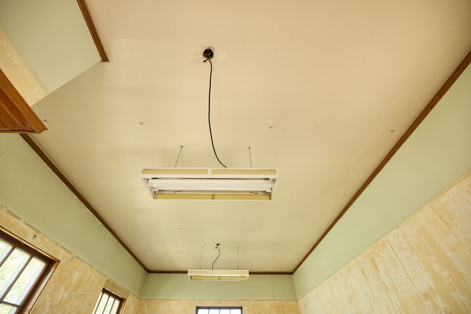Empty room interior with fluorescent lighting fixtures mounted on a plain ceiling.