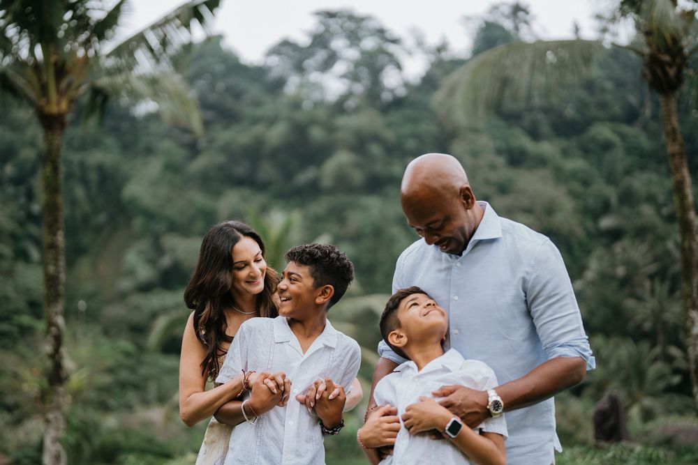 Intimate family moments captured against tropical greenery backdrop.