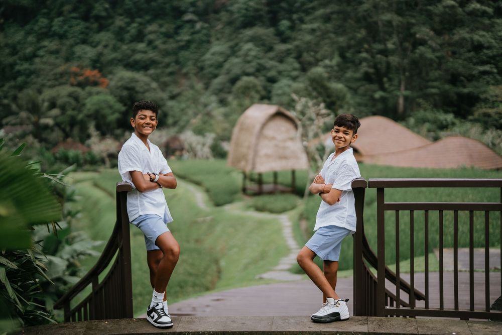 Family shares tender moments on wooden deck surrounded by tropical landscape.