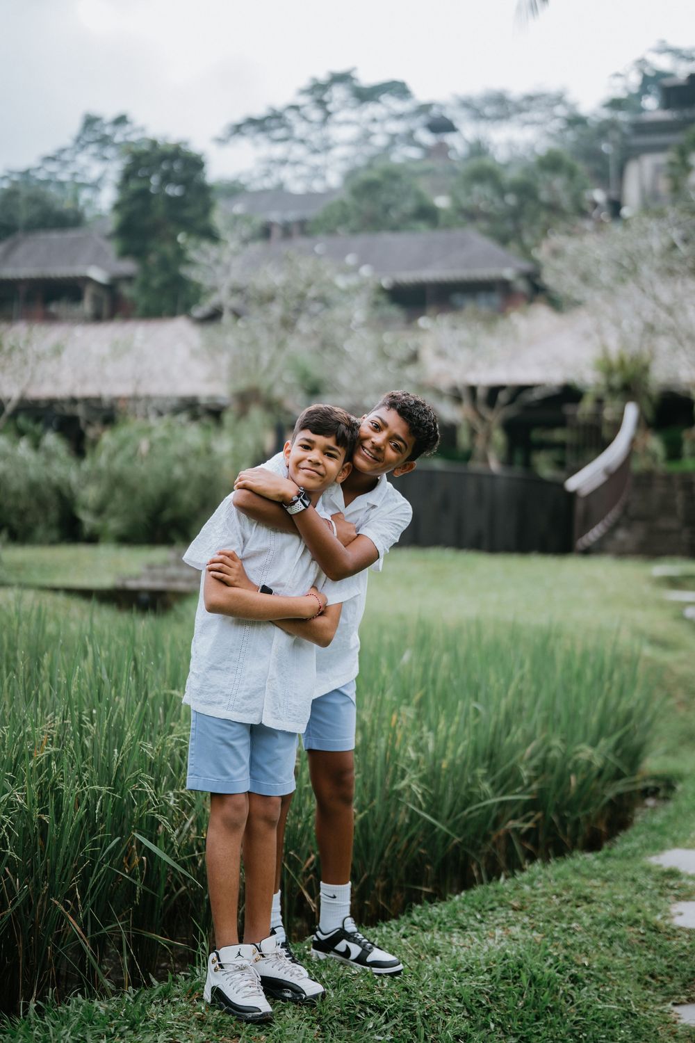 Loving embrace between family members in grassy tropical landscape.