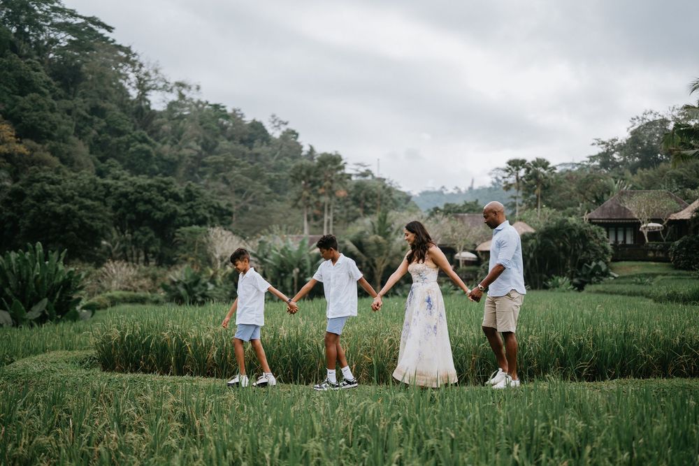 A group walks hand in hand through a scenic rice field landscape in Bali.