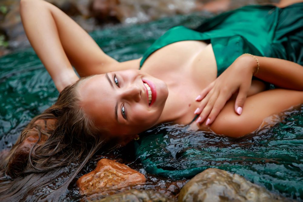 A figure in an emerald green dress strikes elegant poses against a dark textured backdrop for a fashion photoshoot series.