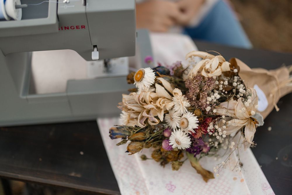 Floral arrangements of dried flowers and preserved botanicals line up in a rustic studio setting.