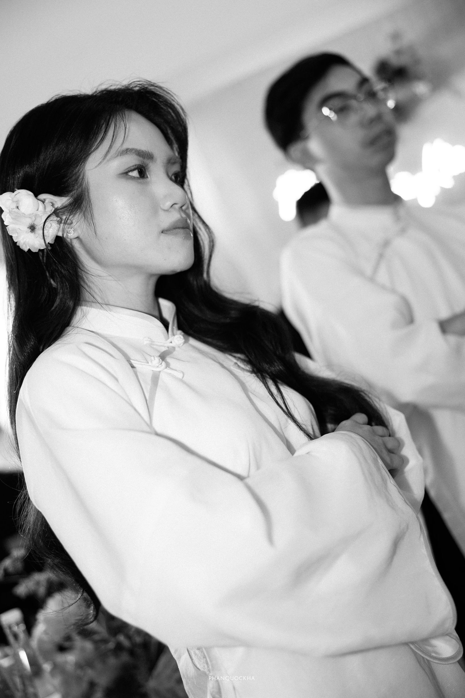 Black and white portrait of a young Vietnamese woman with flower in hair at a formal ceremony.