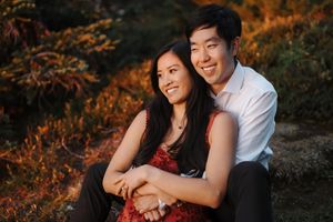 Romantic couple poses together during golden hour in a scenic outdoor setting with warm autumn tones.