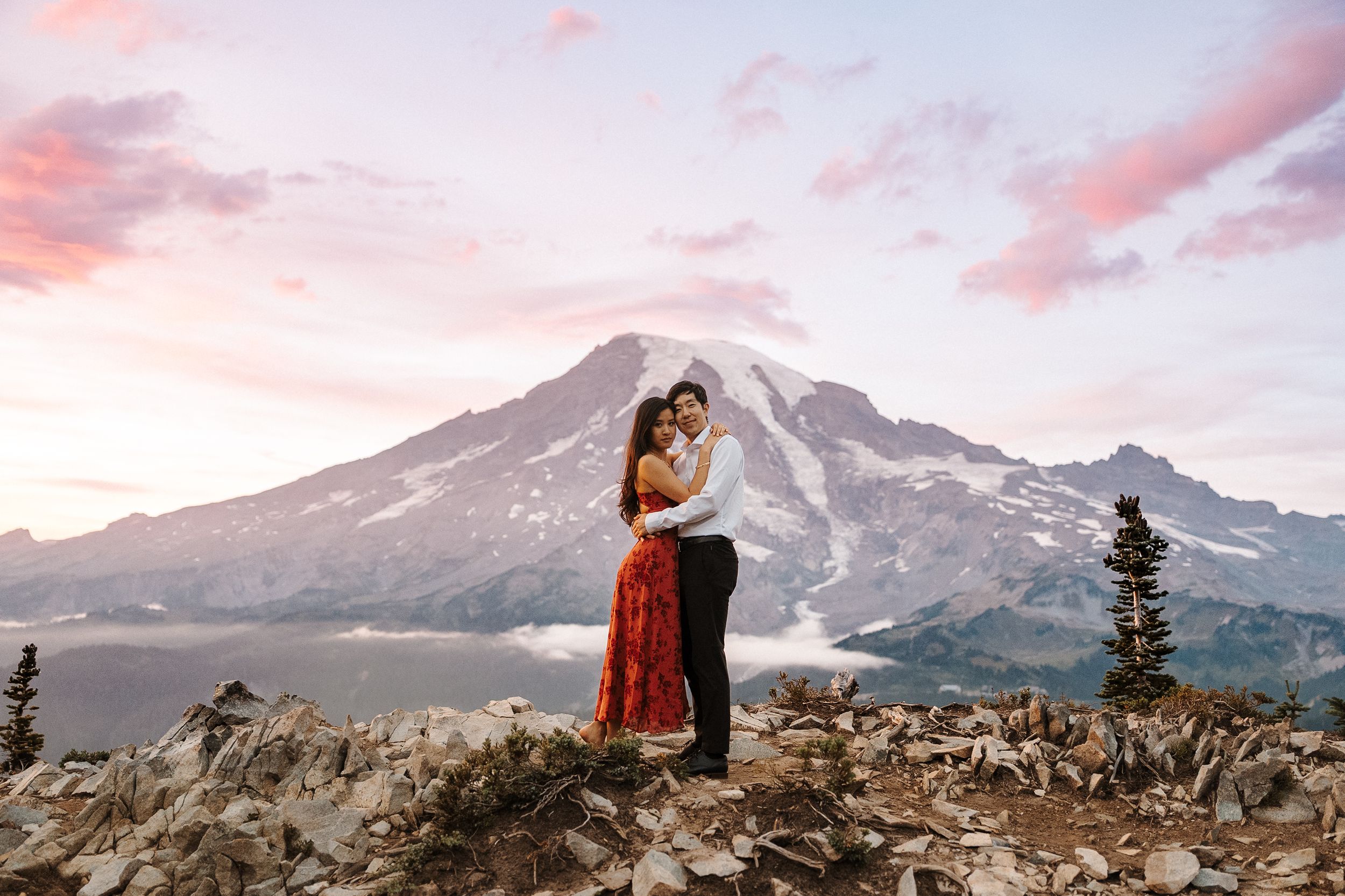 A couple stands silhouetted against a dramatic mountain landscape during sunset in a series of panoramic photos.