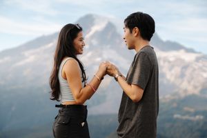Two silhouettes dance and laugh together against a backdrop of rolling mountains on a summer evening.