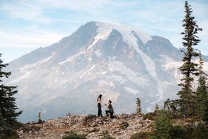People stand on a rocky outcrop overlooking scenic Mount Rainier in Mount Rainier National Park.