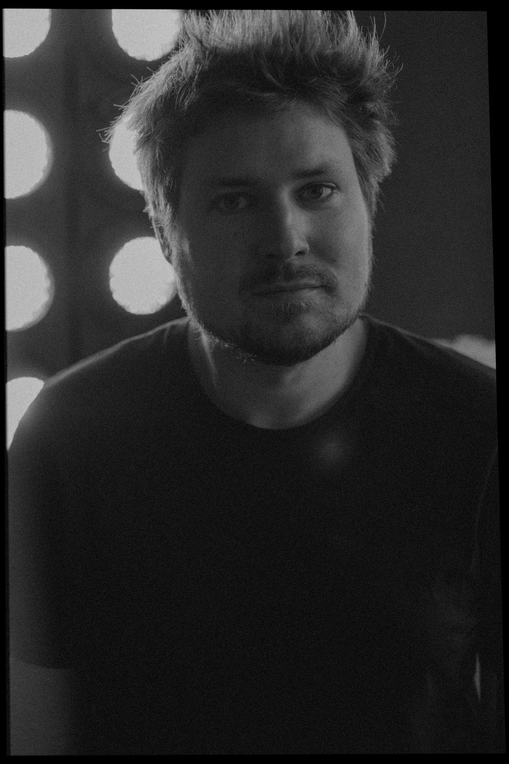 Black and white cinematic close-up portrait showcasing dramatic lighting and atmospheric shadows.