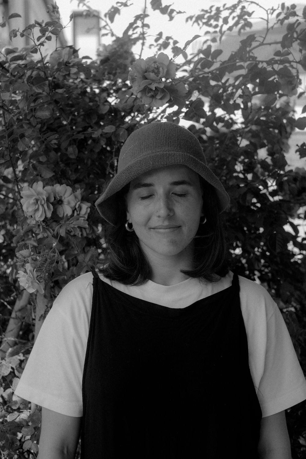 A black and white photo series showing someone wearing a sunhat in dappled light through tree leaves and branches.