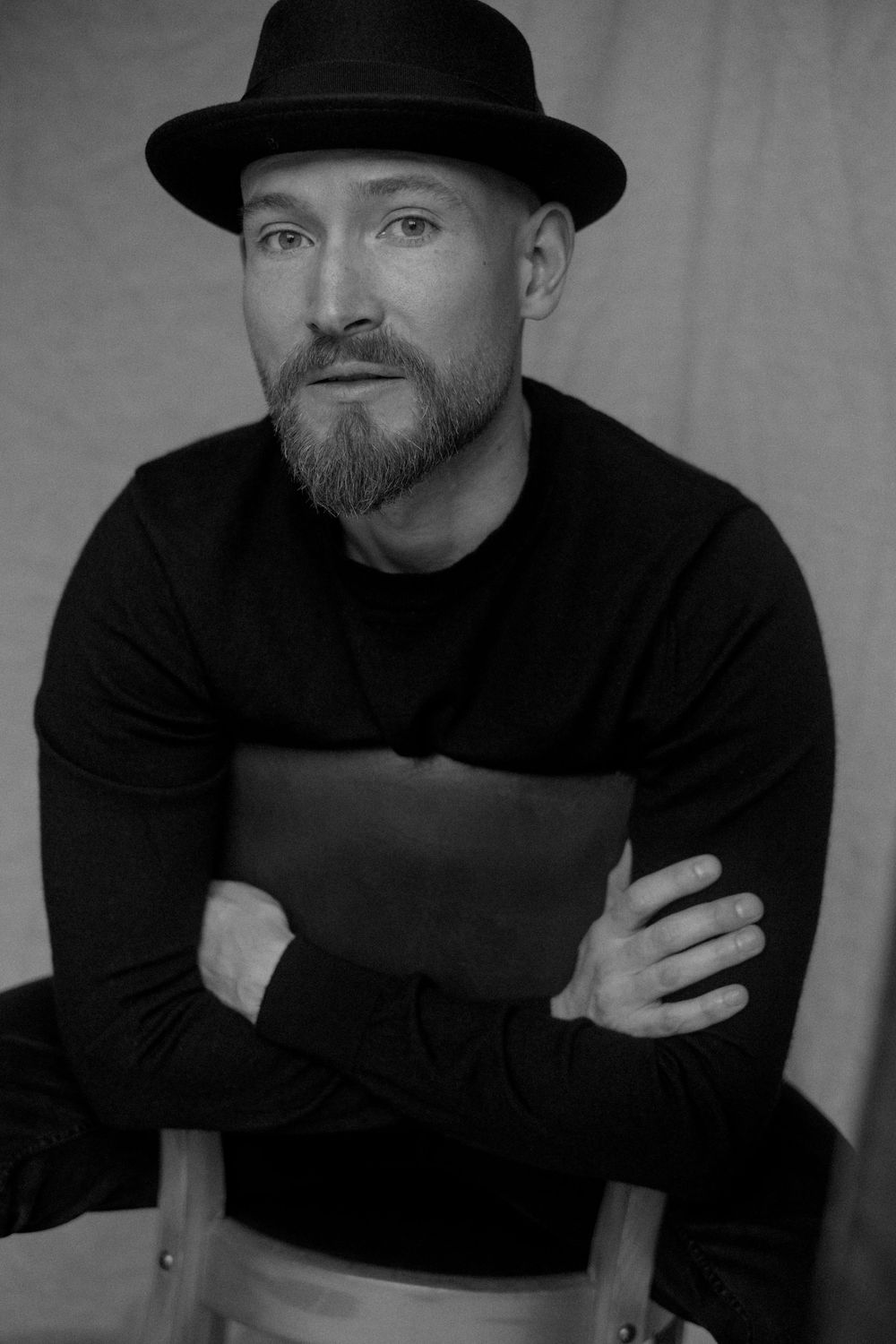 Black and white portrait series showing person in dark turtleneck and hat making expressive poses against light background.