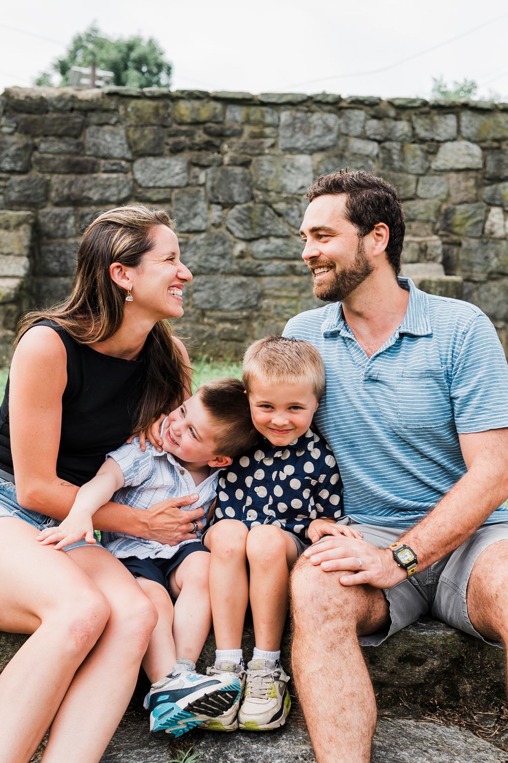 Five sequential candid photos of a family sitting against a stone wall during an outdoor photo session.