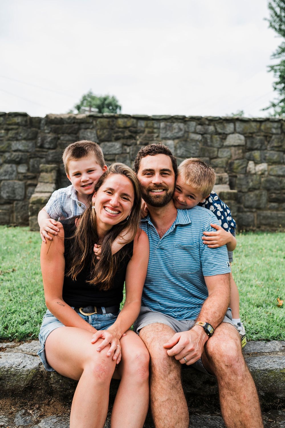 A joyful group sits together on stone steps outdoors, sharing warm embraces and laughter.