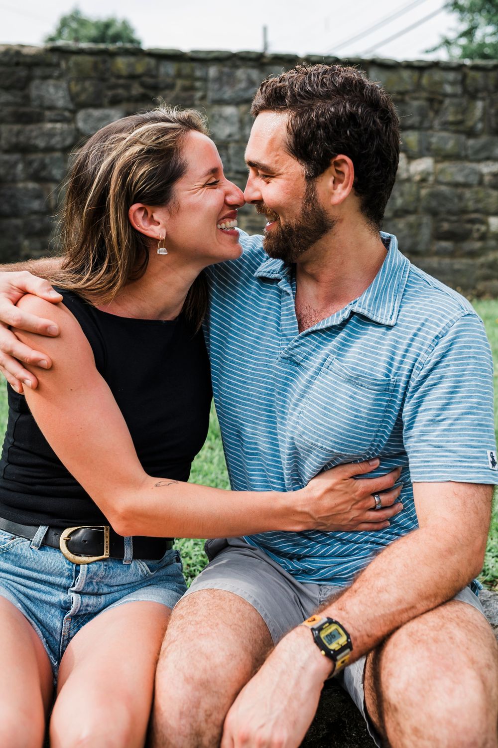 A couple shares intimate moments while sitting together on stone steps outdoors.