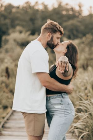Couple embracing in outdoor field setting wearing coordinated white and khaki casual outfits.