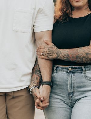 Close-up shot showing hands with tattoos and casual clothing including denim and white tops.