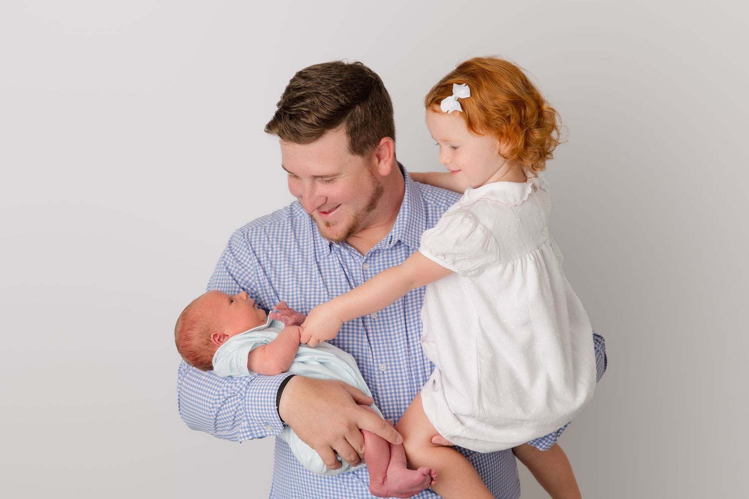 Studio portraits of a family posing together in navy and blue-checkered outfits.