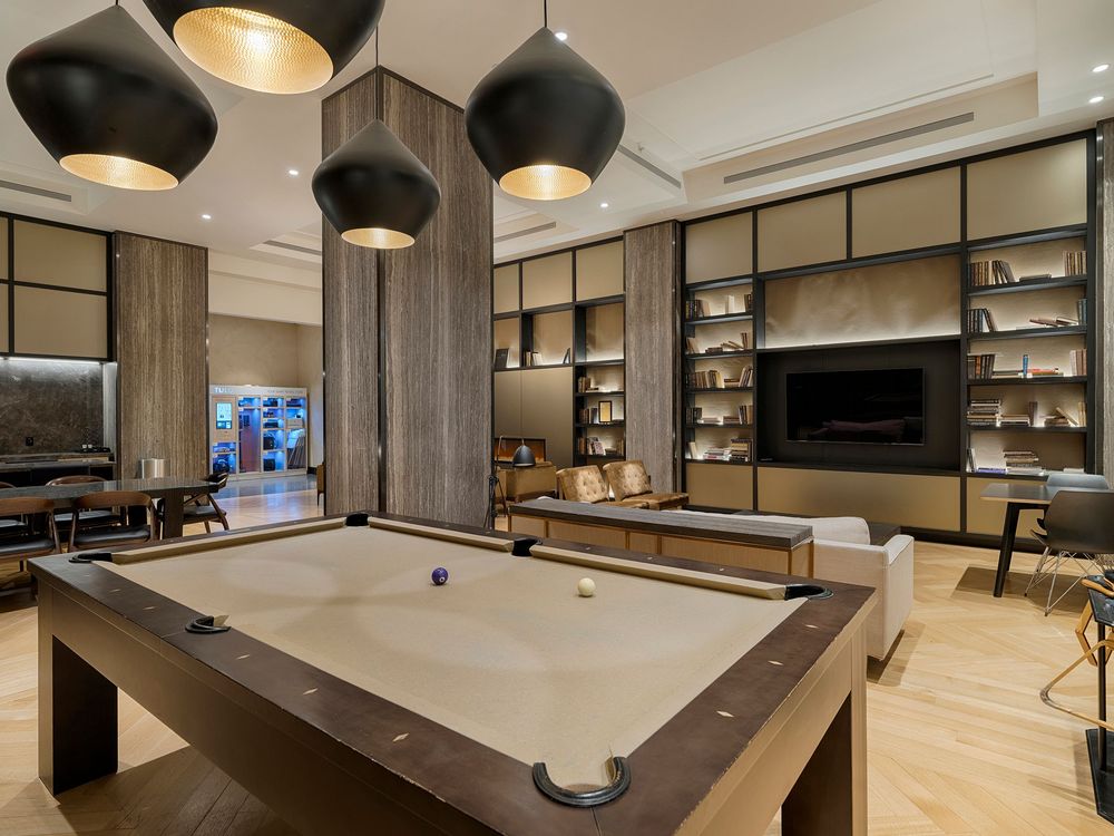 Modern luxury apartment interior featuring dark pendant lights, wood accents, and a sleek pool table in an open layout space.