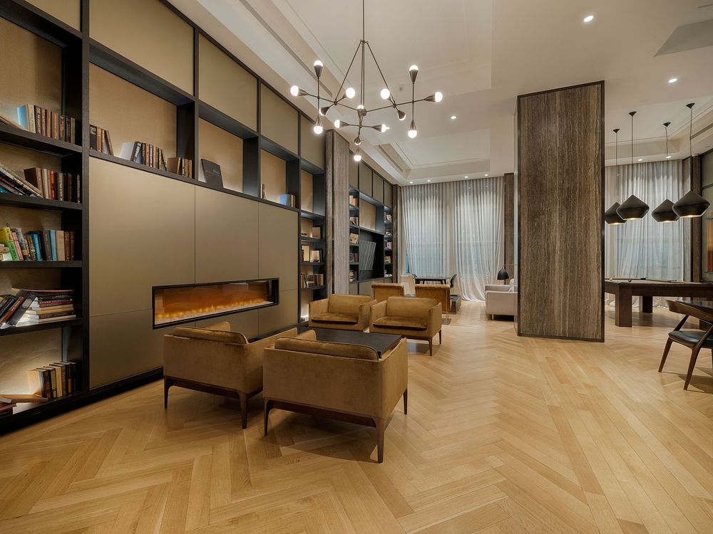 Modern apartment interior with chevron wood flooring, pendant lights and luxury furnishings in warm neutral tones.