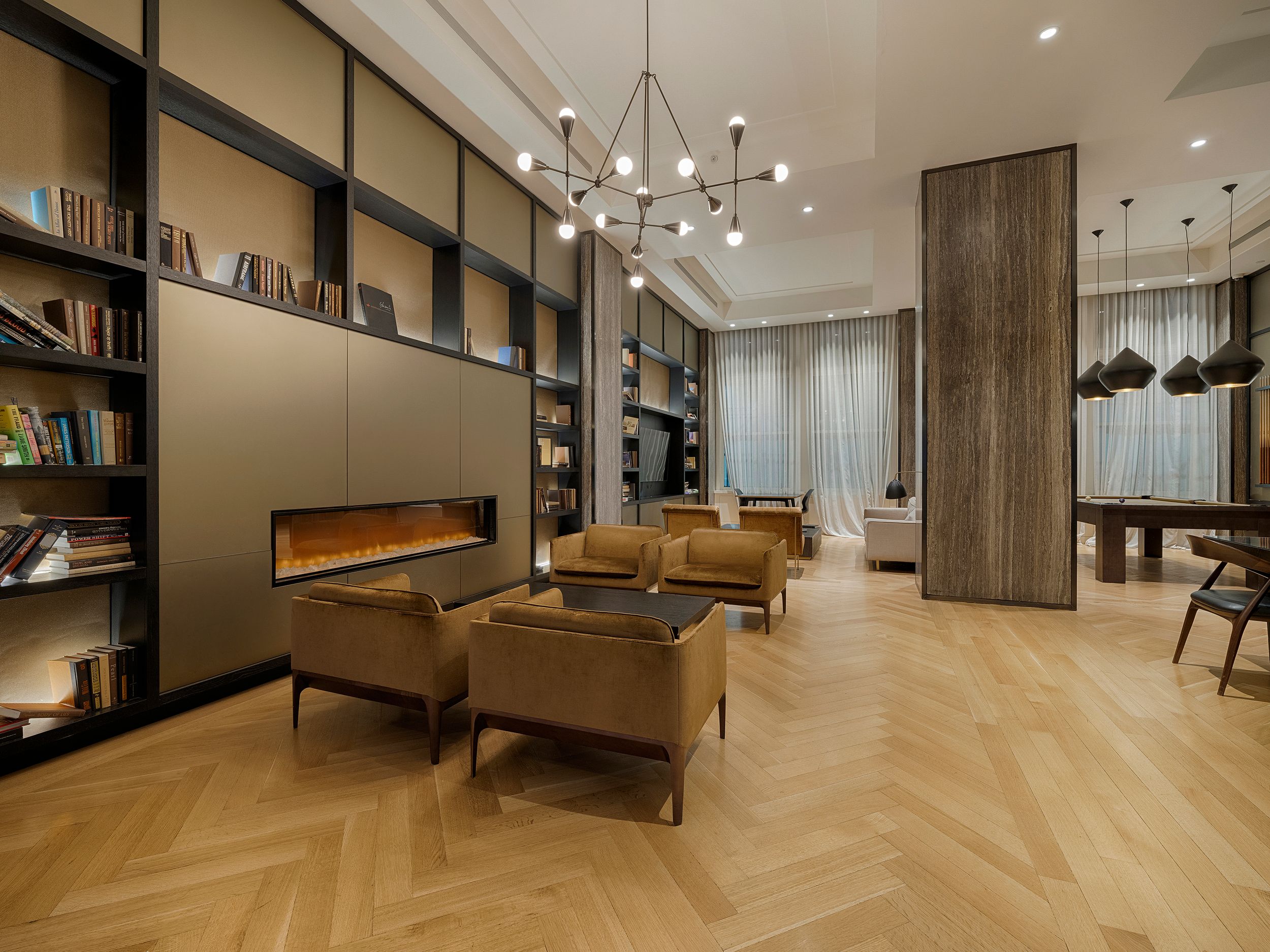 Modern apartment interior with chevron wood flooring, pendant lights and luxury furnishings in warm neutral tones.