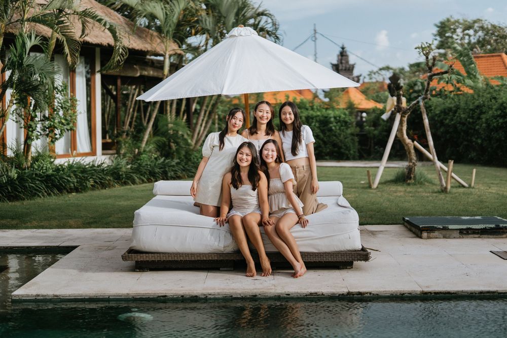 Friends enjoying a relaxing day at a tropical resort with poolside loungers and umbrellas.