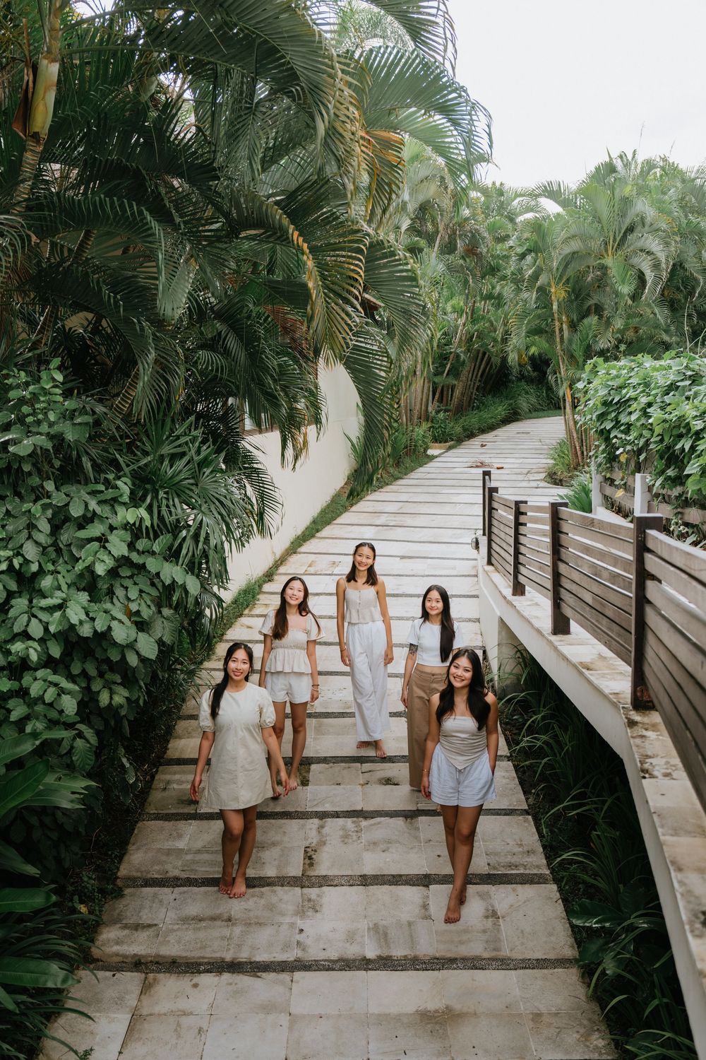 Group walking down wooden pathway surrounded by lush tropical vegetation.