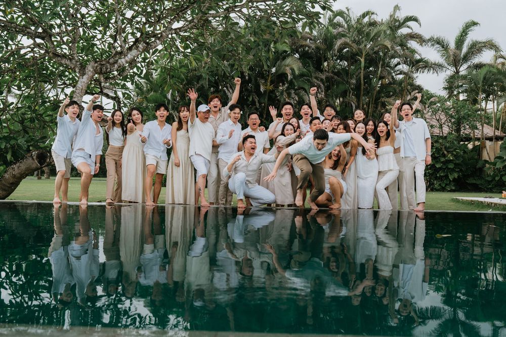Group photo session by a reflective pool surrounded by palm trees.