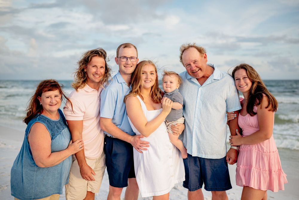 A series of candid beach portraits showing a family group in coordinated blue and white outfits against an ocean backdrop.