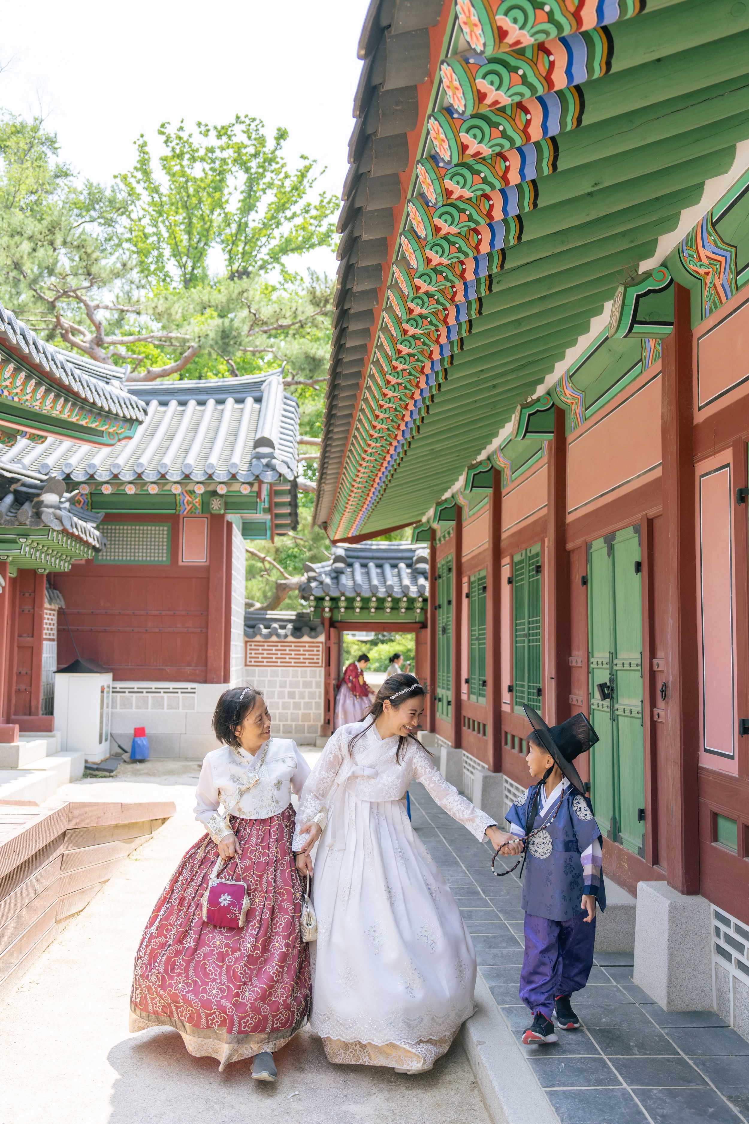 People wearing colorful hanbok dresses walking through traditional Korean palace corridors.