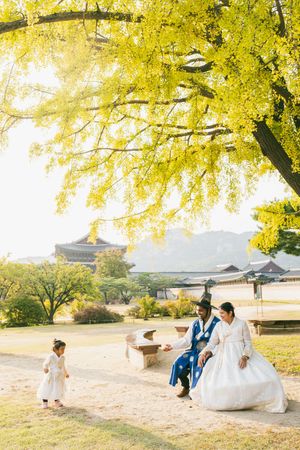 Wedding photoshoot under yellow ginkgo trees at a traditional Korean palace during autumn.