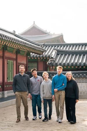 Group photo taken in front of traditional Korean palace architecture with white walls and tiled roofs.