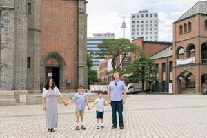 Family walking together on stone plaza in front of historic brick church building.
