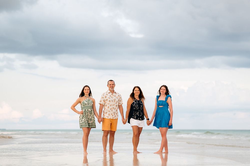A series of seven panoramic beach photos showing people walking and playing on a sandy shore with cloudy skies.