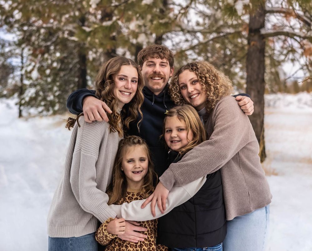 Casual winter family photoshoot with everyone wearing neutral toned sweaters in the snow.